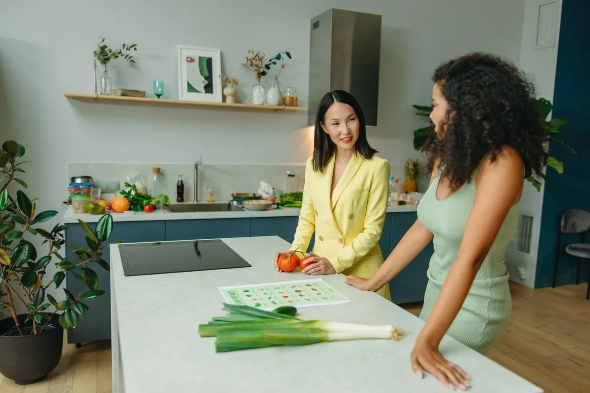 Two women discussing healthy eating with vegetables on the kitchen counter.