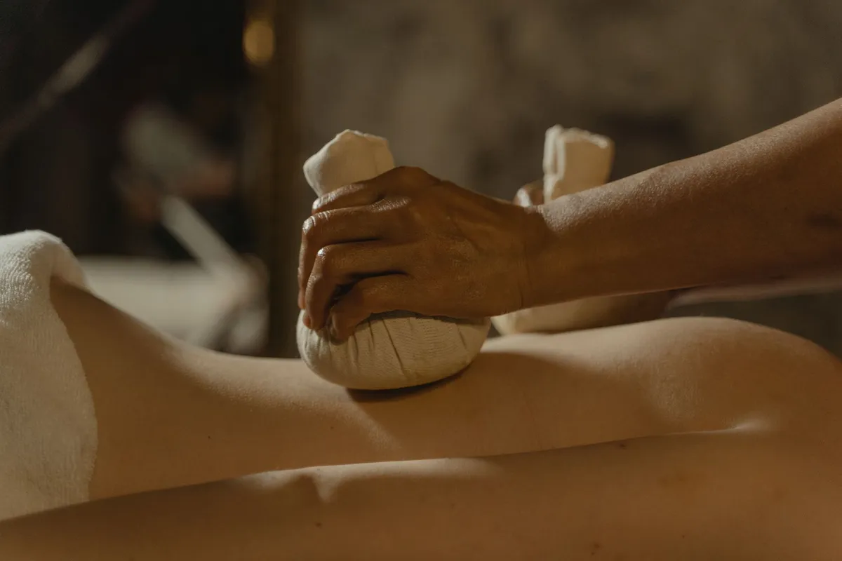 Hand applying a warm compress to the back during a treatment session.