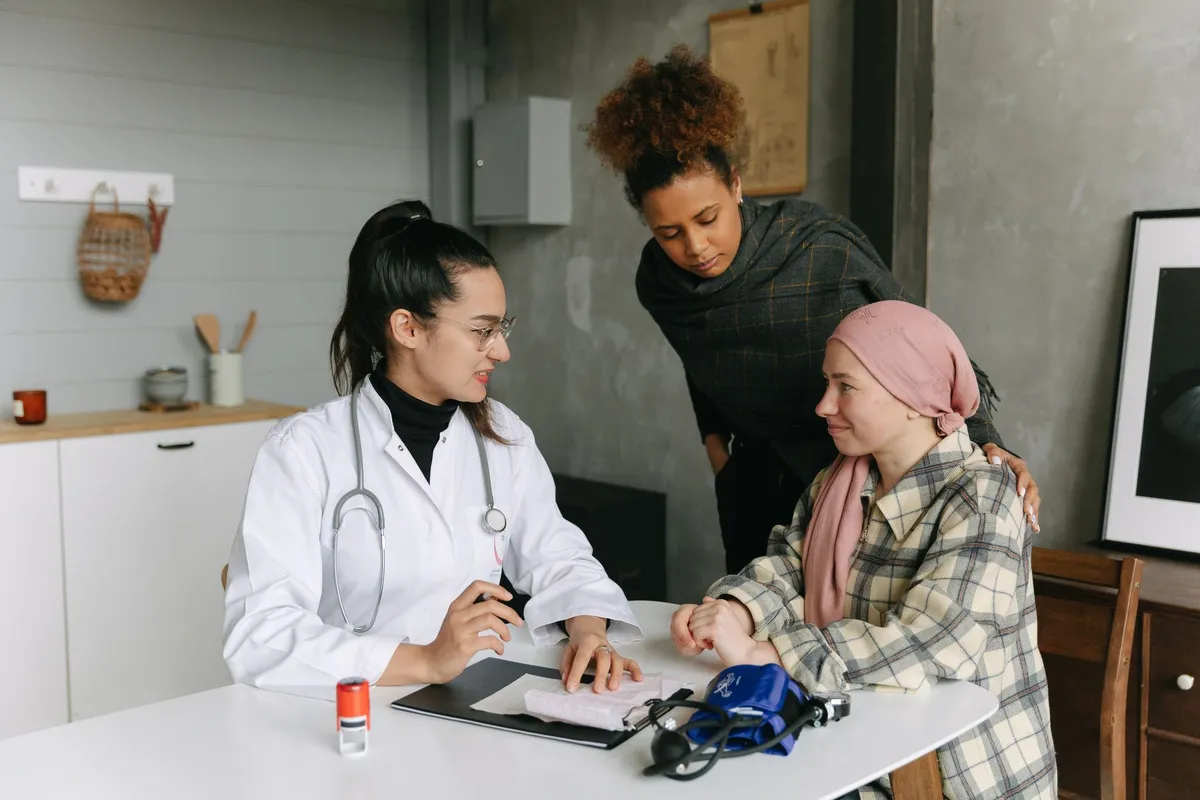Doctor consulting with a cancer patient and a support person in a clinical setting.