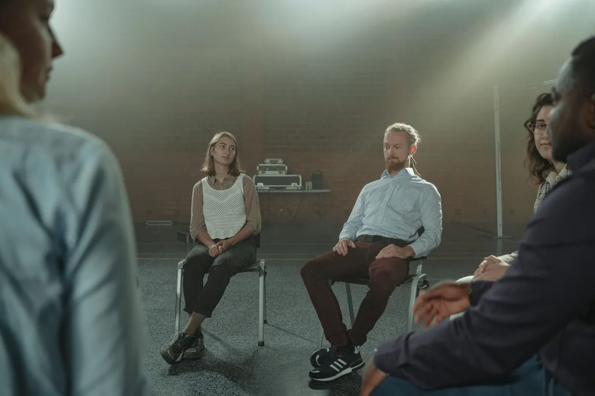 Participants in a support group sitting in a circle, engaged in discussion.