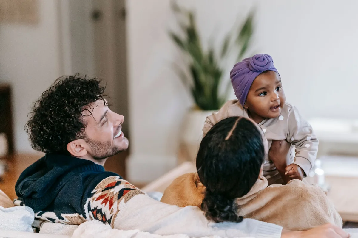 Parents interacting with a baby in a cozy home setting.