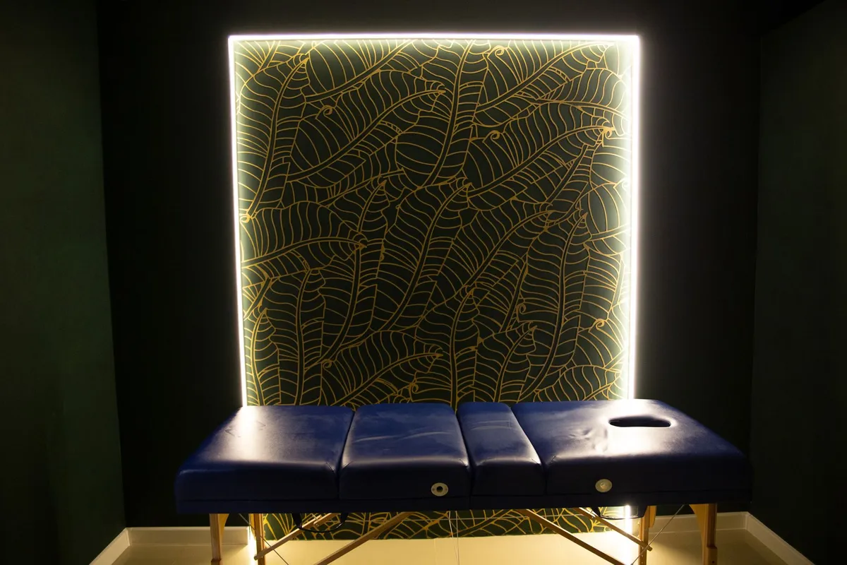 A massage table in a softly lit therapy room with a decorative wall.