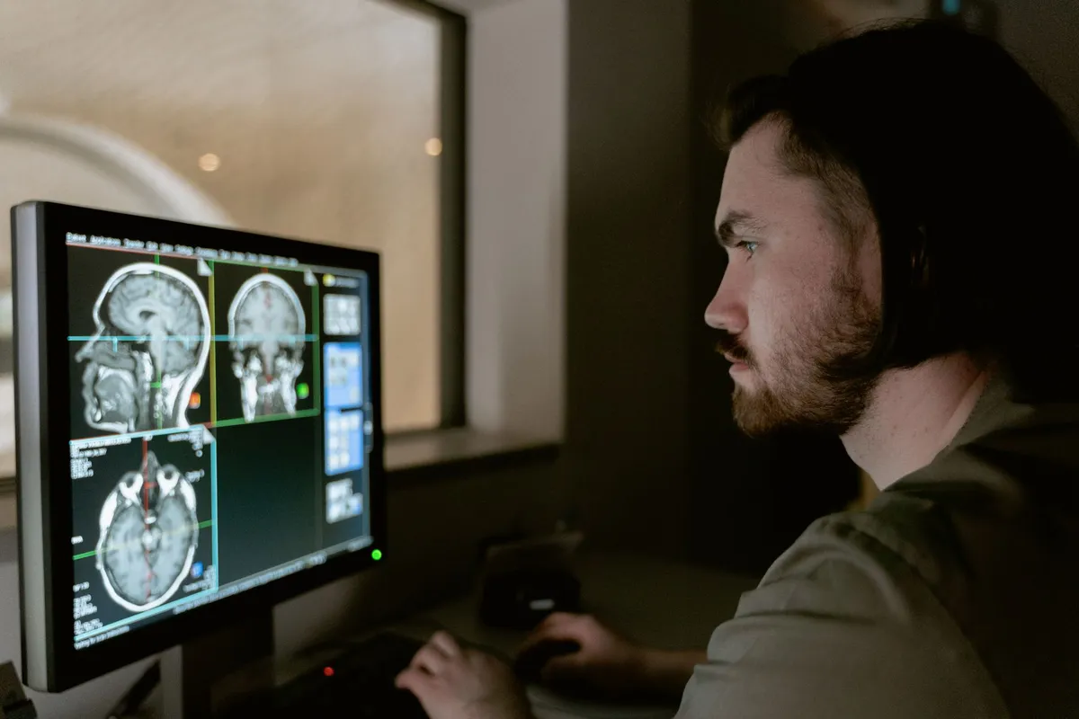 Medical professional analyzing brain scans on a computer screen in a clinical setting.