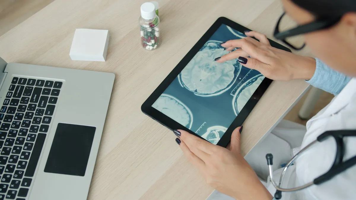 Doctor examining brain scans on a tablet in a clinical setting.