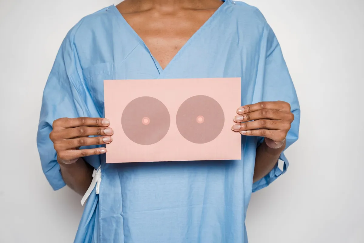 Person in a medical gown holding a diagram of breasts for awareness education.