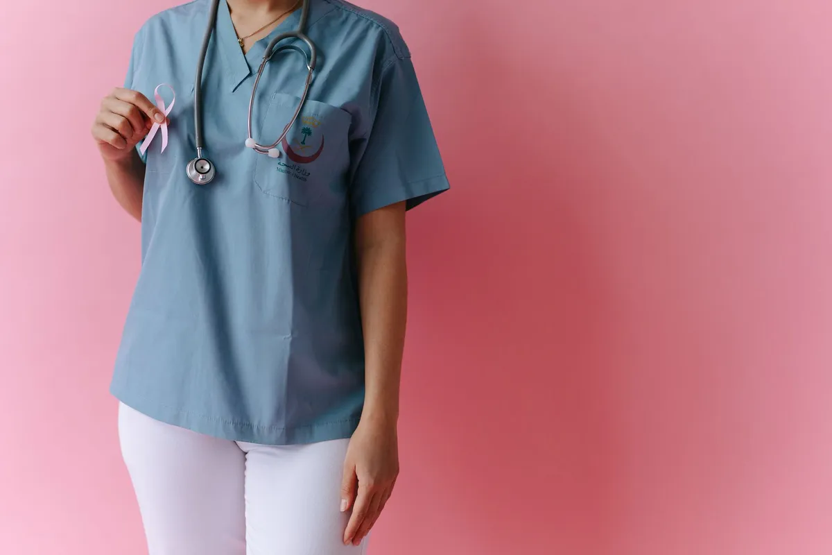 Healthcare professional holding a pink ribbon symbolizing breast cancer awareness.