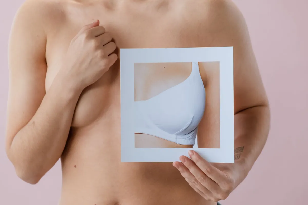 Person holding a picture of a breast in a bra, illustrating breast size and shape.