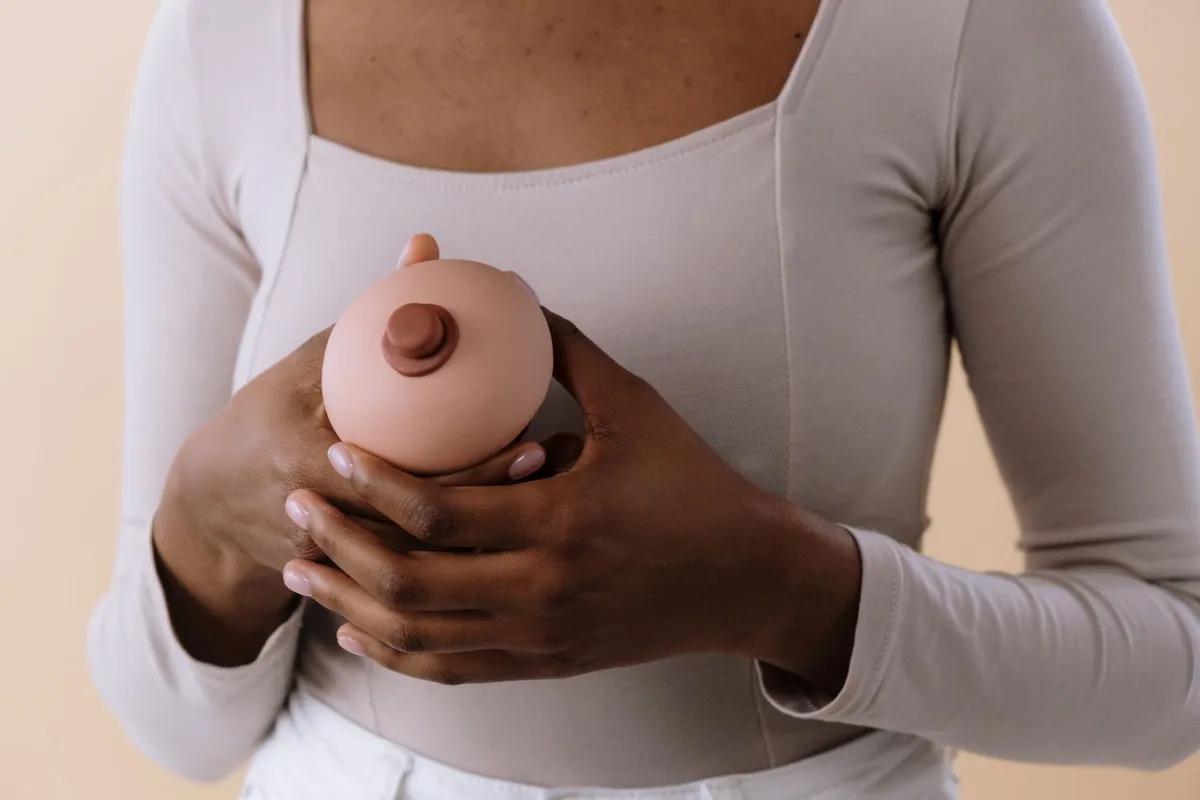 Person holding a realistic breast model, illustrating breastfeeding context.
