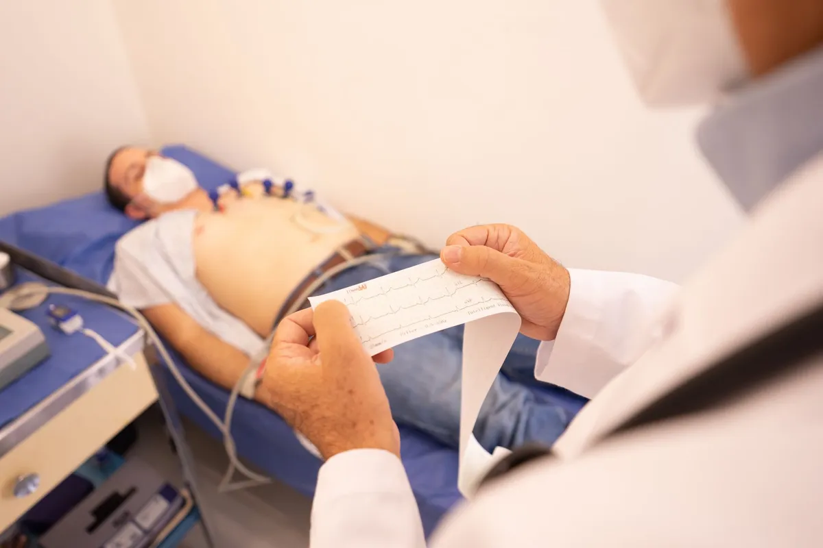 Doctor examining a patient’s ECG while they lie on an exam table.