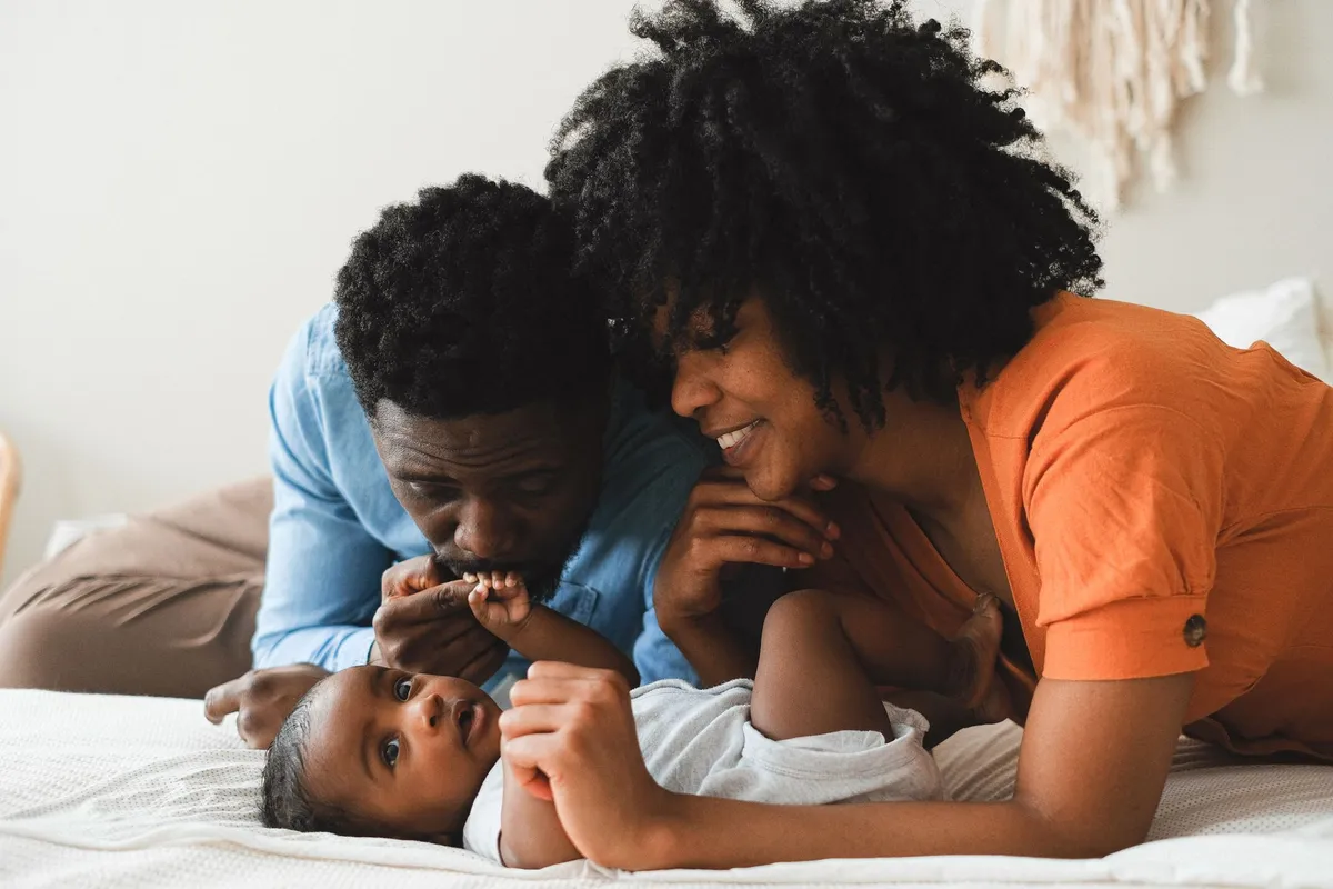 Parents interacting with a baby on a bed, showcasing a nurturing environment.