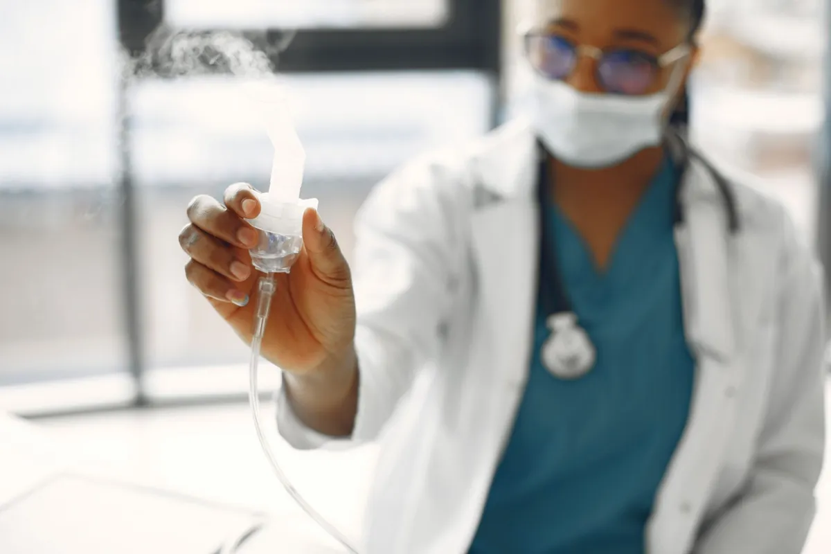 Healthcare professional holding a nebulizer in a clinical setting.