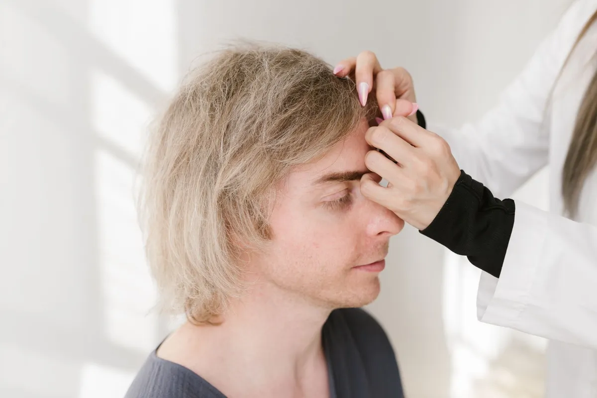 A person receiving a brow lift consultation with a practitioner examining their forehead.