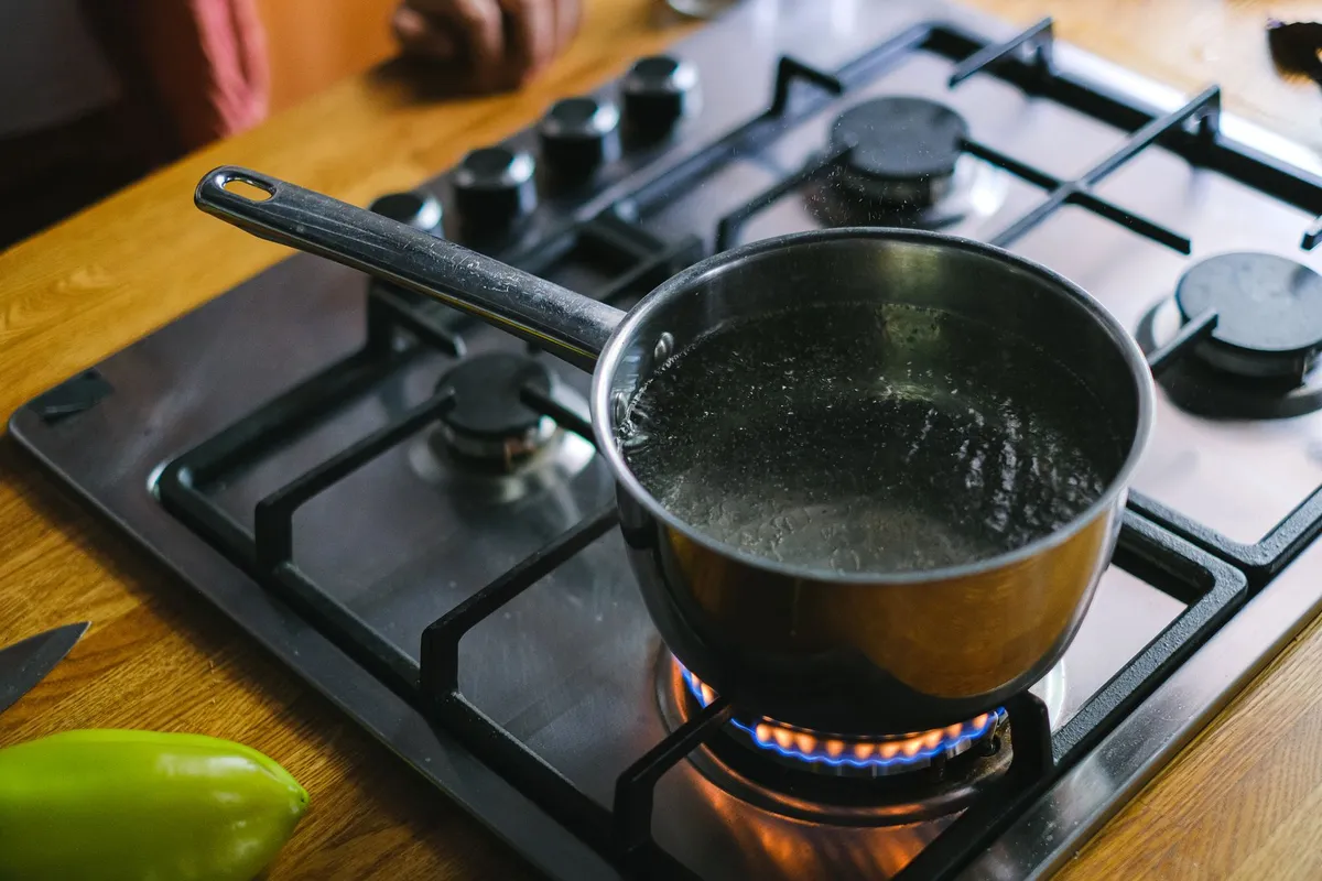 Pot of boiling water on a stove with bubbles rising.