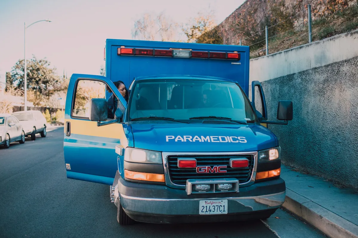 Ambulance with paramedics at the scene, parked on a street.