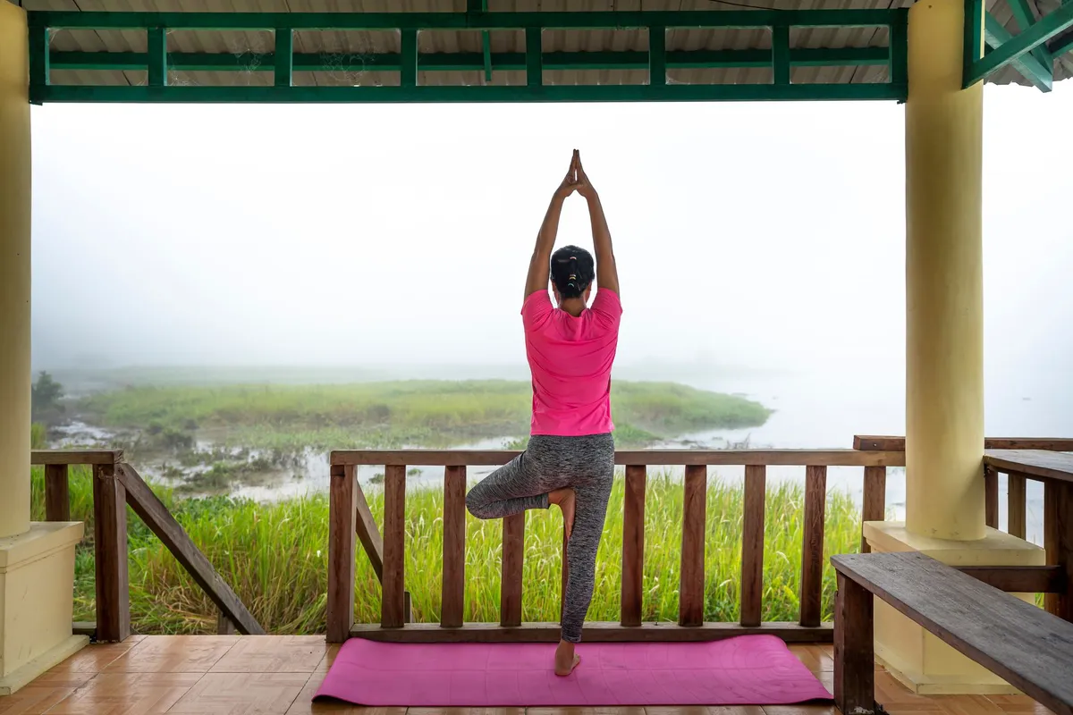 Woman practicing yoga on a mat with a serene view of nature in the background.