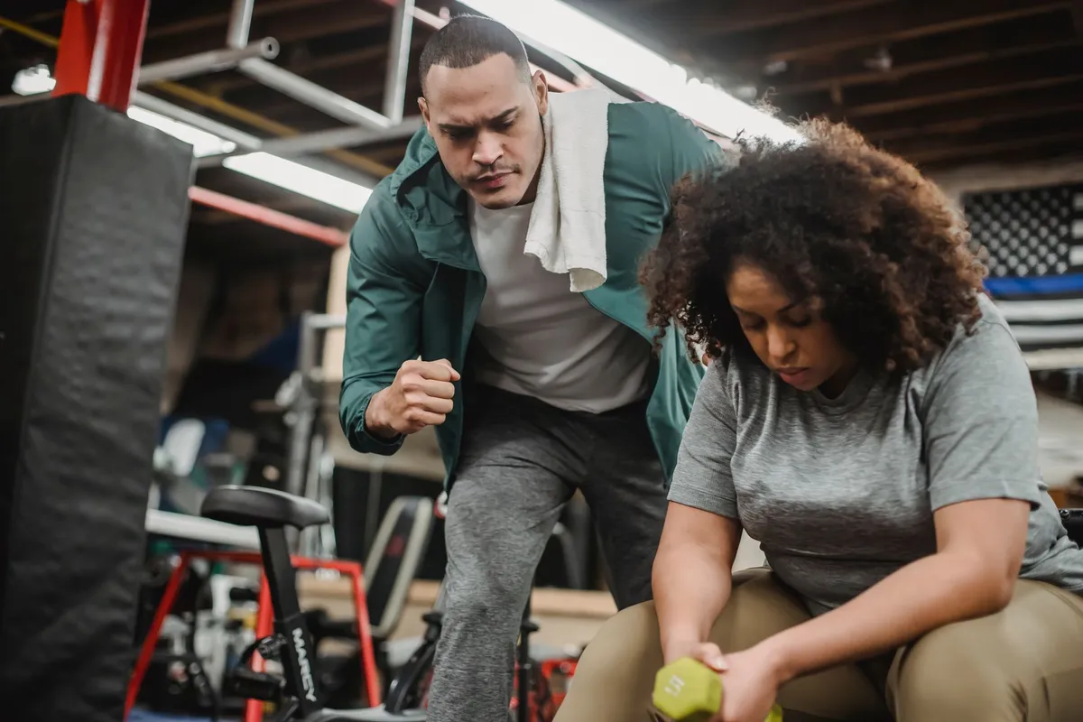 Personal trainer assisting a client with weights in a gym setting.