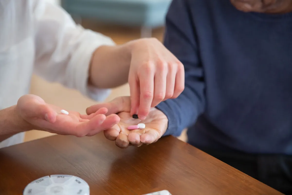 Hands showing pills for medication management between two people.