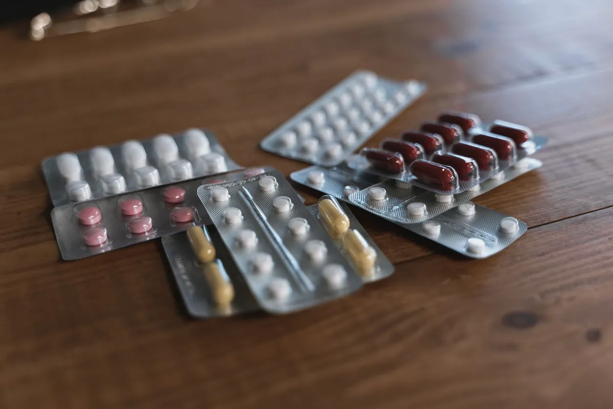 Various pain relief medications in blister packs on a wooden table.