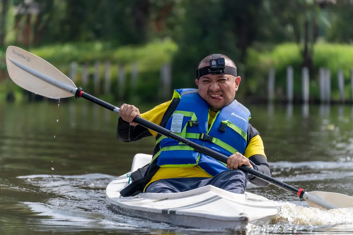 Person kayaking in a life jacket with a paddle, focused on the water.