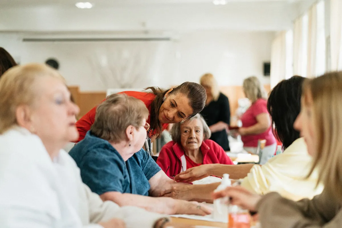 Caregiver interacting with elderly individuals at a support group meeting.