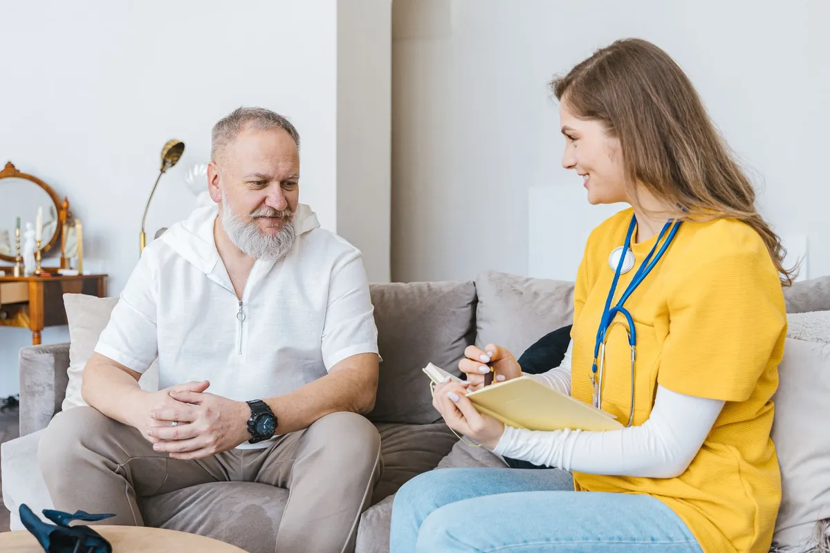 A nurse discussing care with an elderly man in a home setting.