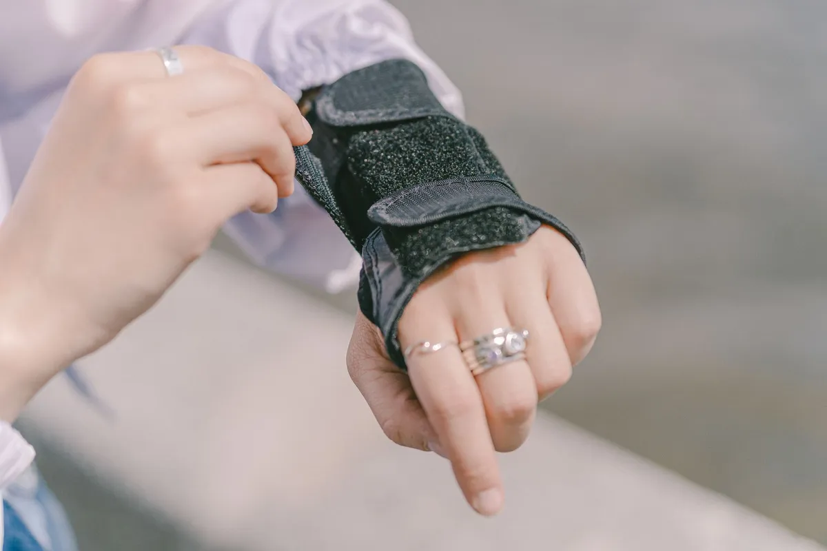 Close-up of a wrist wearing a black brace with straps.