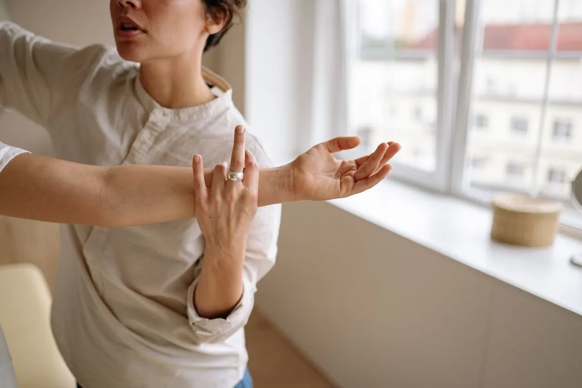 Physical therapist demonstrating wrist exercises to a patient in a bright room.