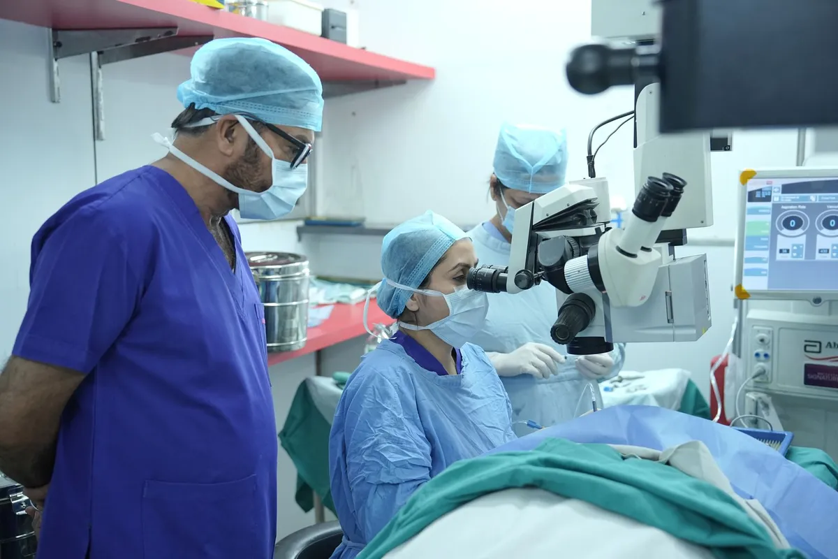 Surgeons performing cataract surgery with a microscope in a clinical setting.
