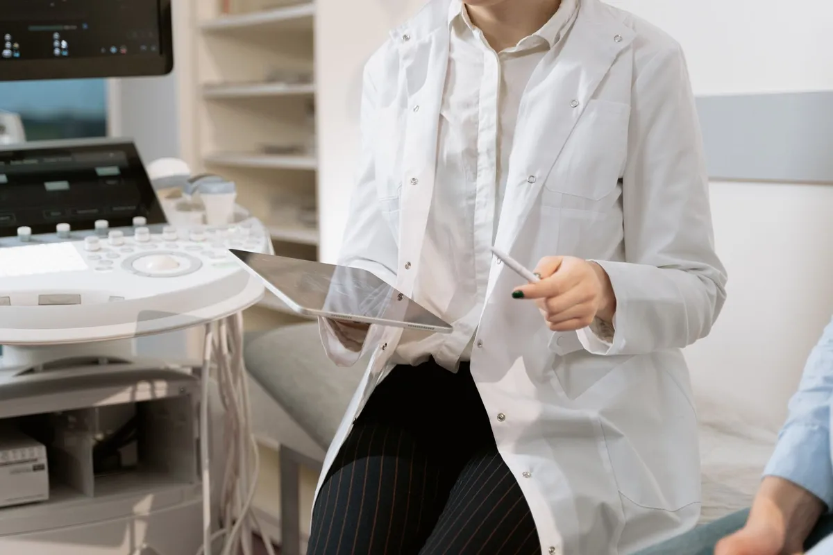 Healthcare worker discussing cervical screening with a patient using a tablet in a clinical setting.
