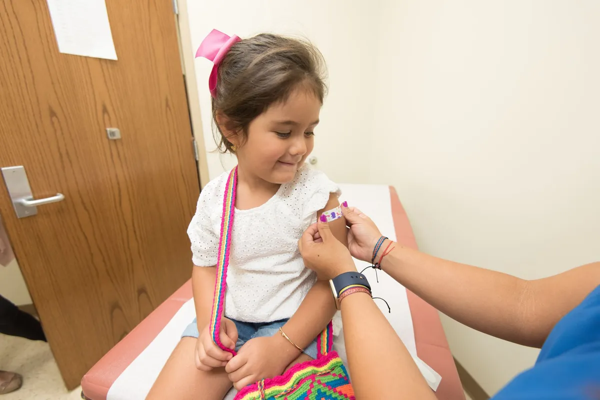 Young girl receiving a vaccination at a clinic, smiling after the shot.