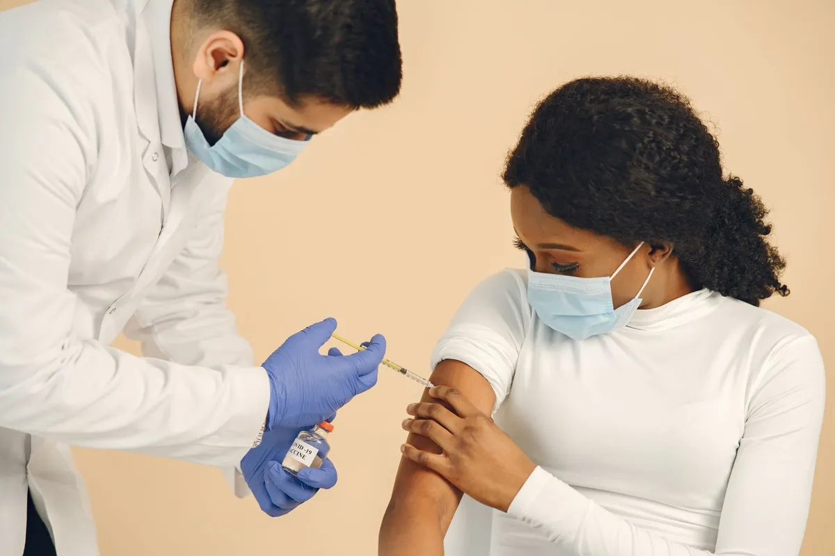 Healthcare professional administering a vaccine to a patient in a clinical setting.