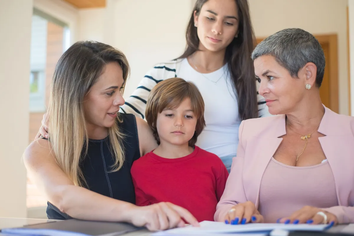Two women and a boy discussing documents at a table, focusing on child safety.