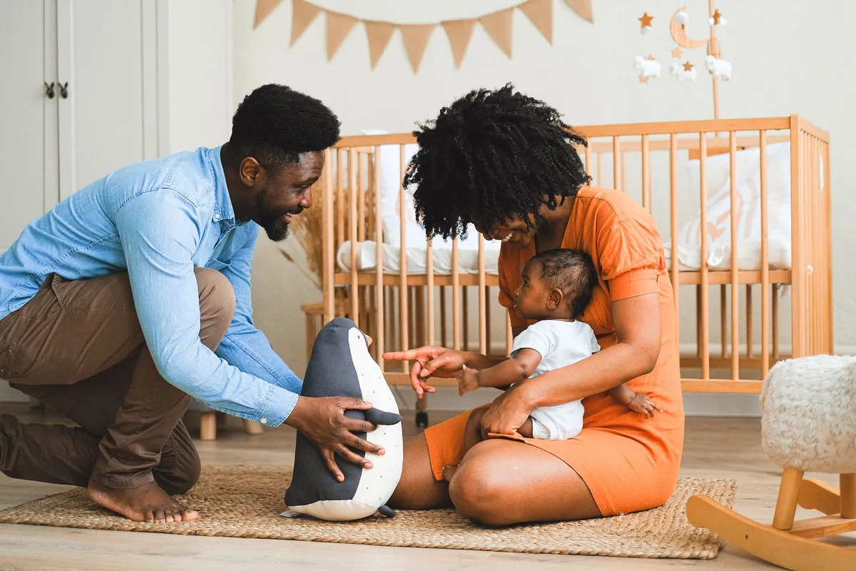Parents playing with their three-month-old baby in a nursery setting.