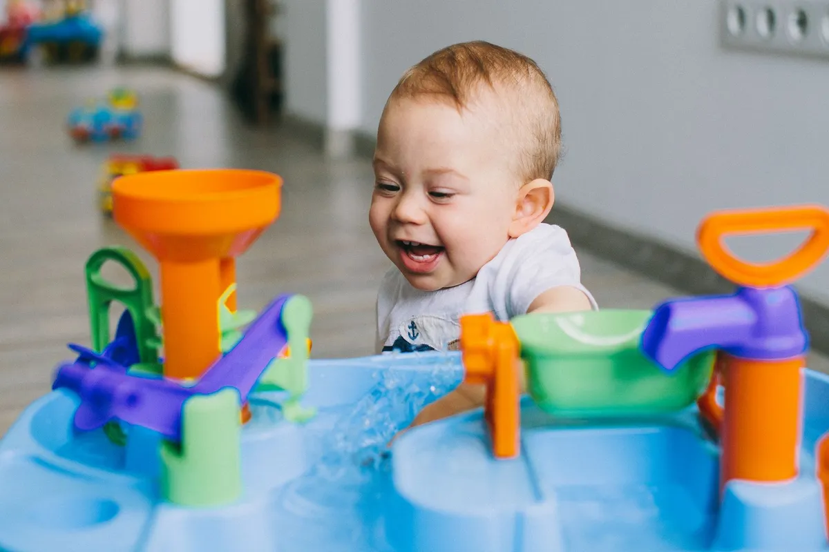 Baby smiling while playing with a water activity table.