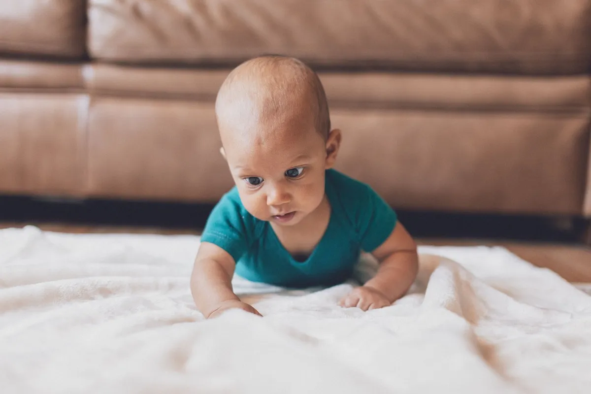 Baby crawling on a soft surface with a focused expression.