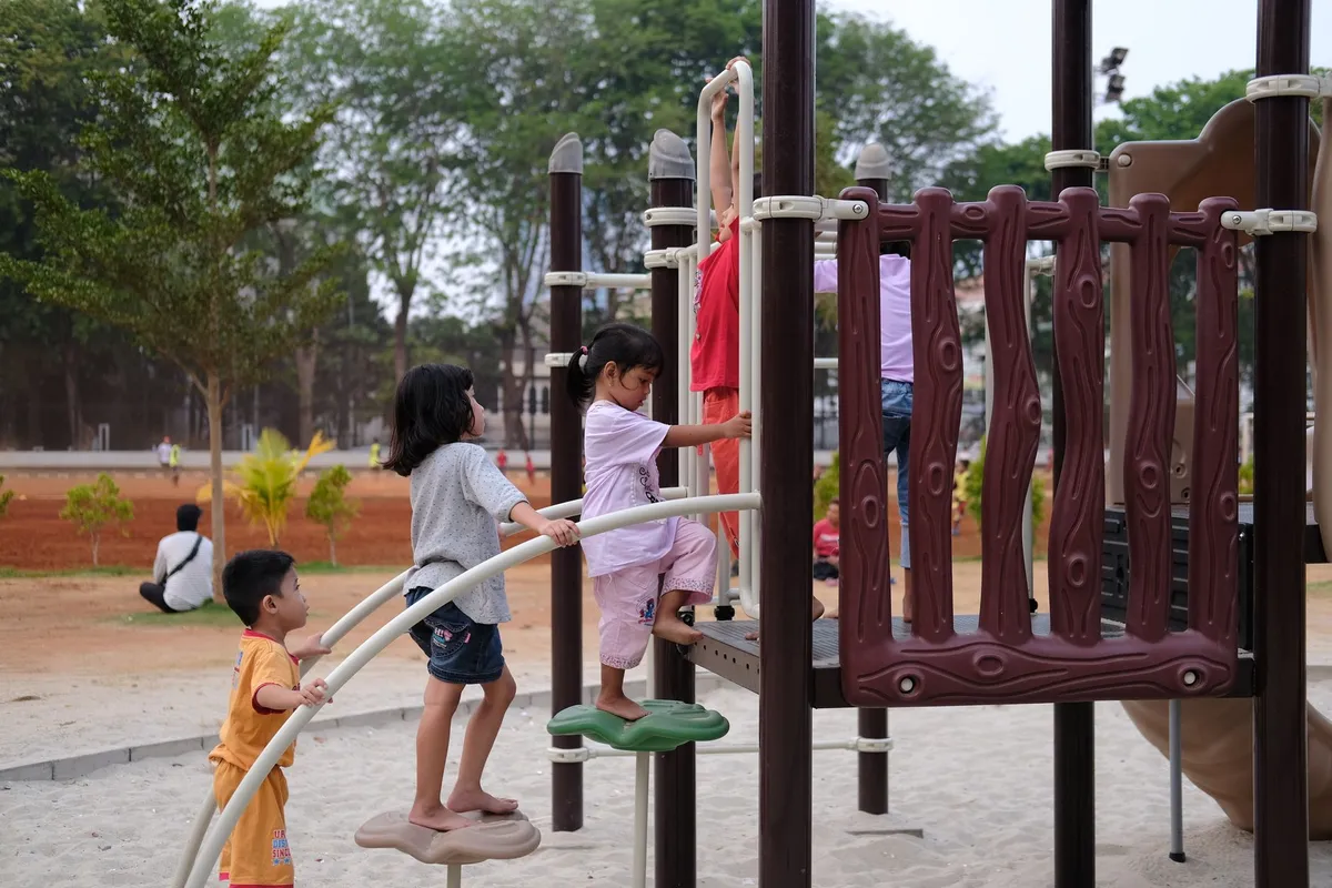 Children climbing on playground equipment in a park setting.