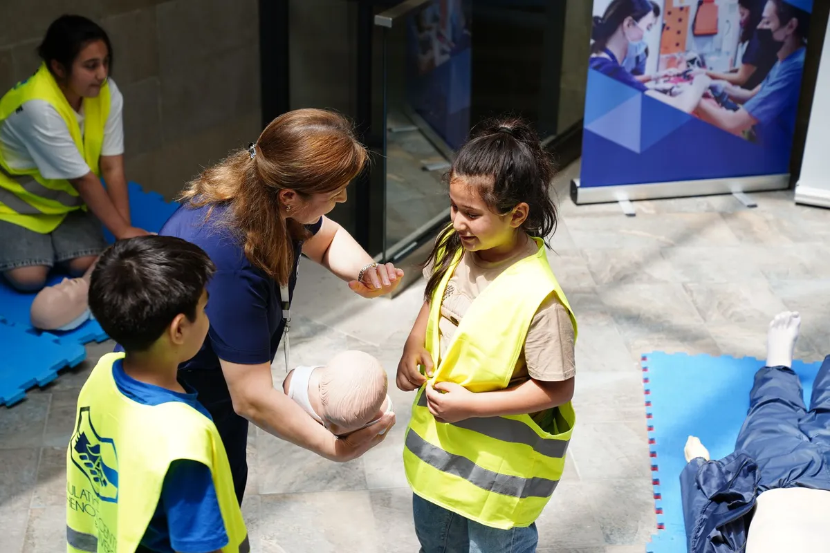Instructor demonstrating first aid techniques to children using a CPR dummy.