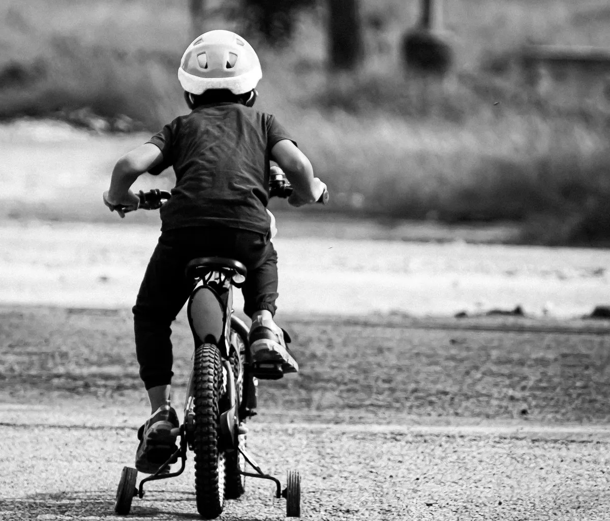Child riding a bicycle wearing a helmet, showing safe cycling practices.