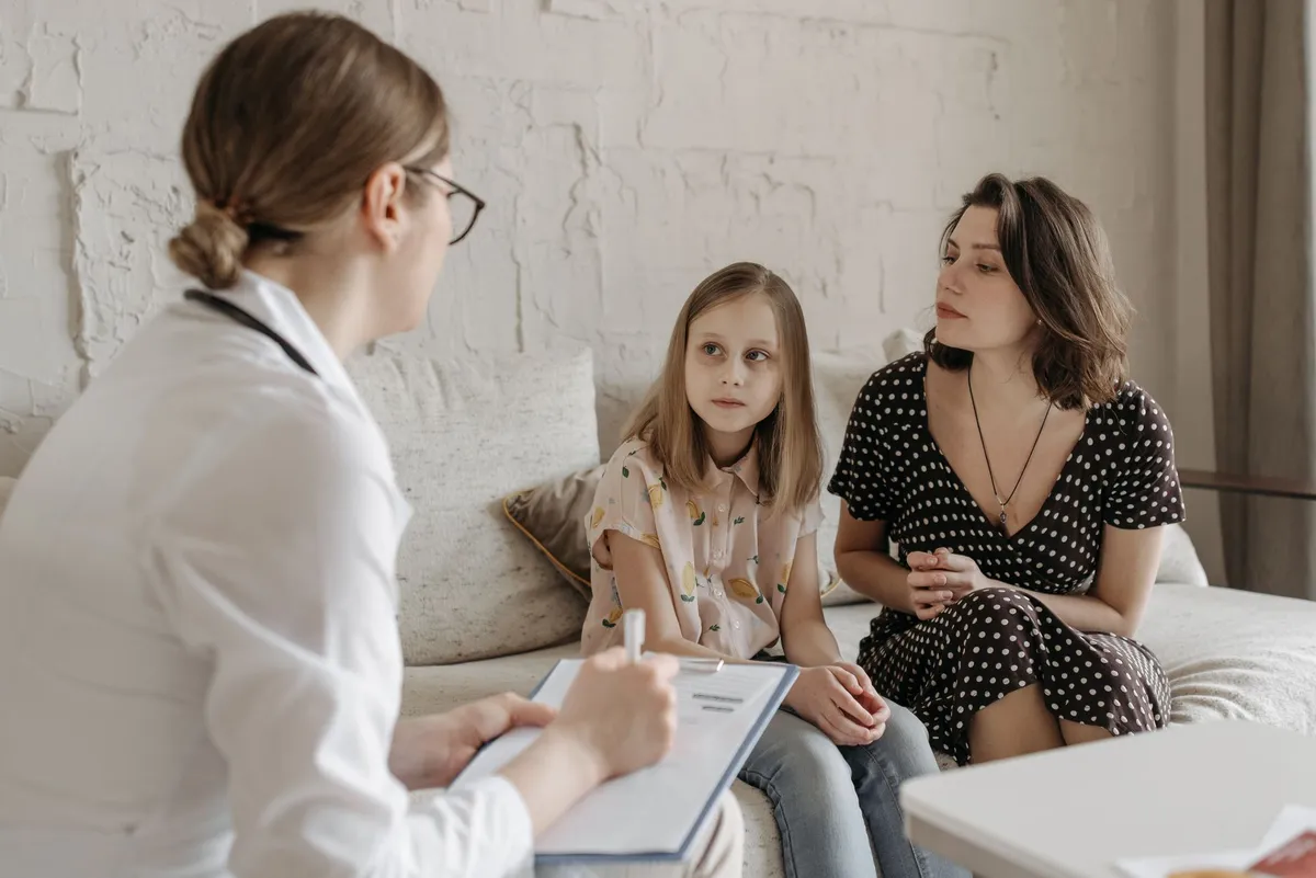 A mother and daughter discussing with a healthcare provider in a cozy setting.
