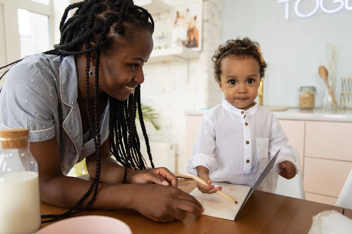 A mother and child engaged in a creative activity at a table with art supplies.