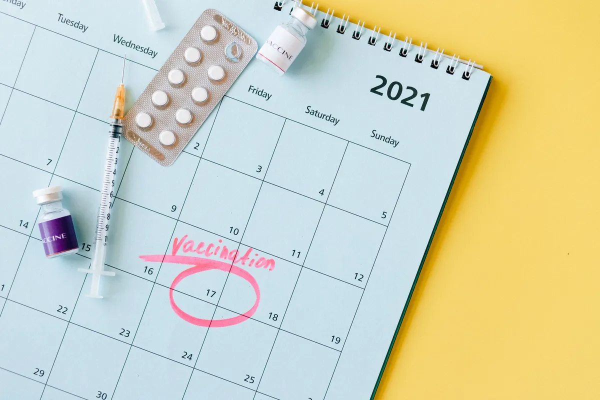 Calendar with marked vaccination date and medical supplies on a yellow background.