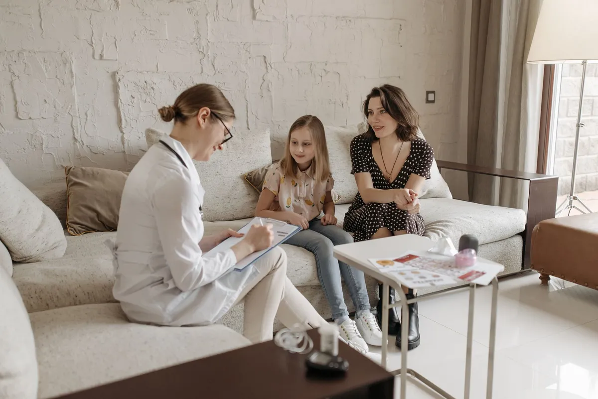 A healthcare professional discussing with a mother and daughter in a comfortable setting.