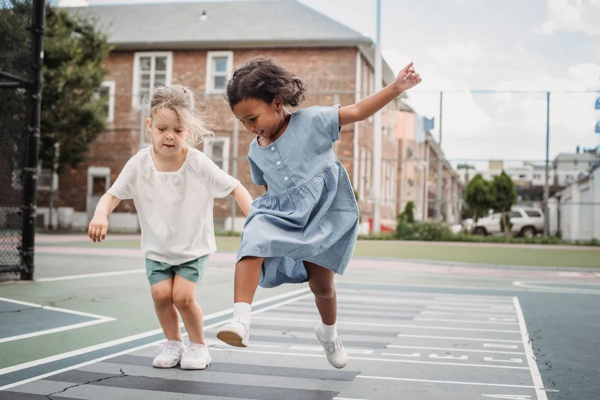 Two young girls playing together on a playground.