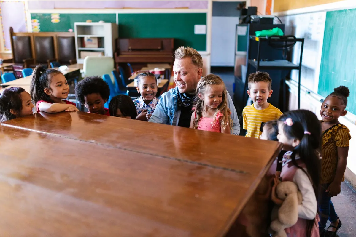 A group of children interacting with an adult in a classroom setting.