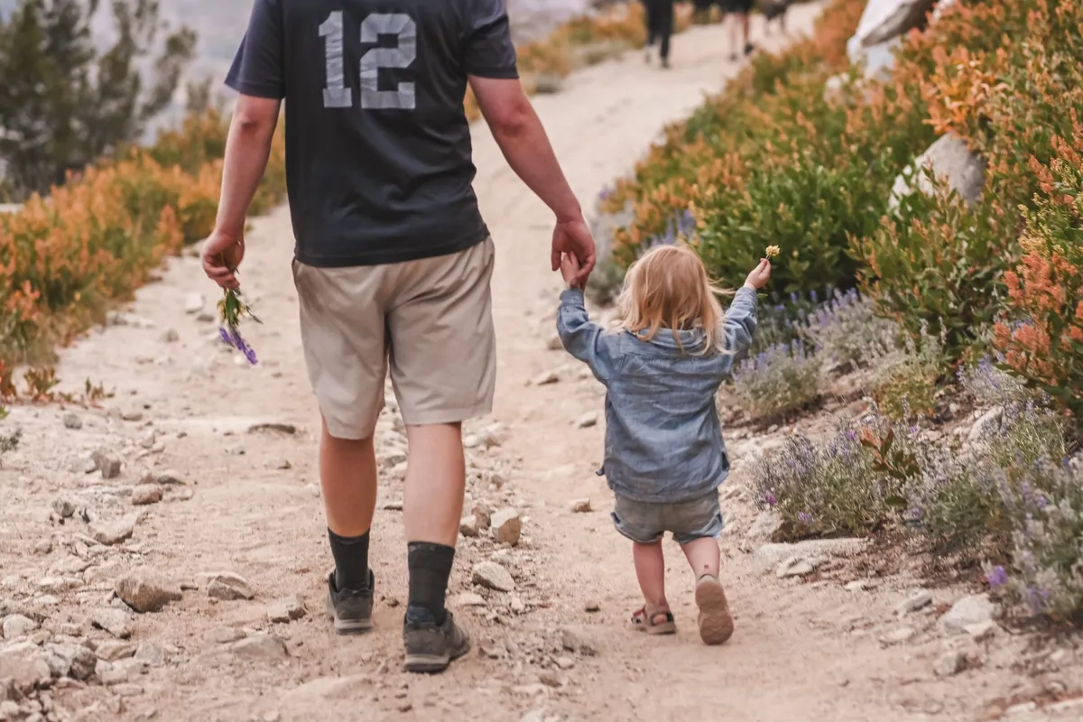 A parent and child walking on a nature trail, enjoying the outdoors together.