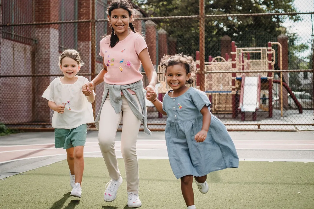 Three children running together on a playground, enjoying free playtime.