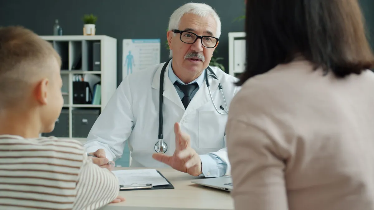 Doctor discussing health information with a patient and child in an office setting.