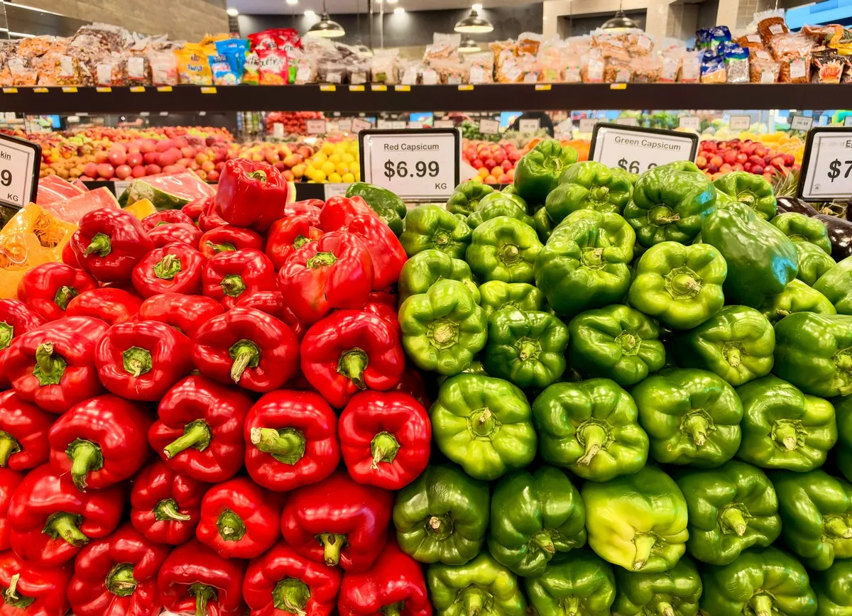 Display of red and green bell peppers in a grocery store aisle