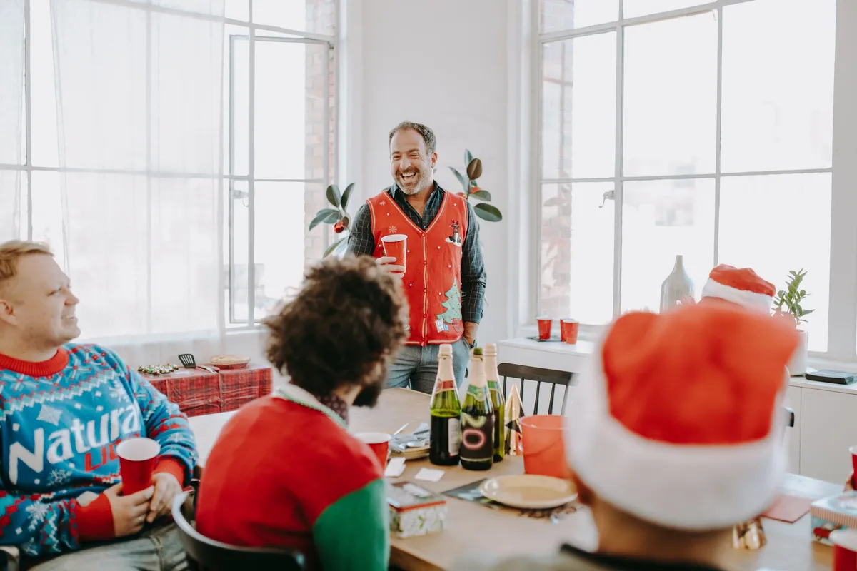Group of friends in festive attire celebrating at a holiday gathering with drinks.