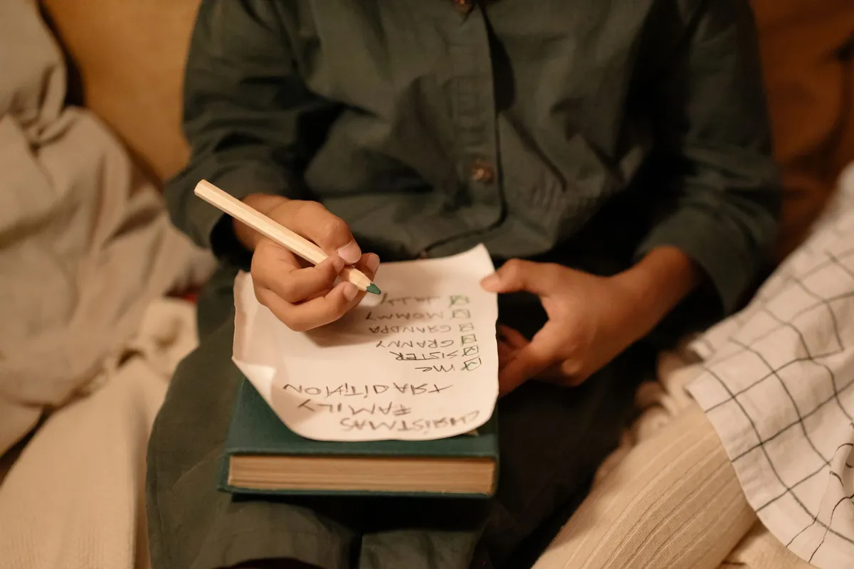 Child writing a Christmas gift list on a piece of paper.